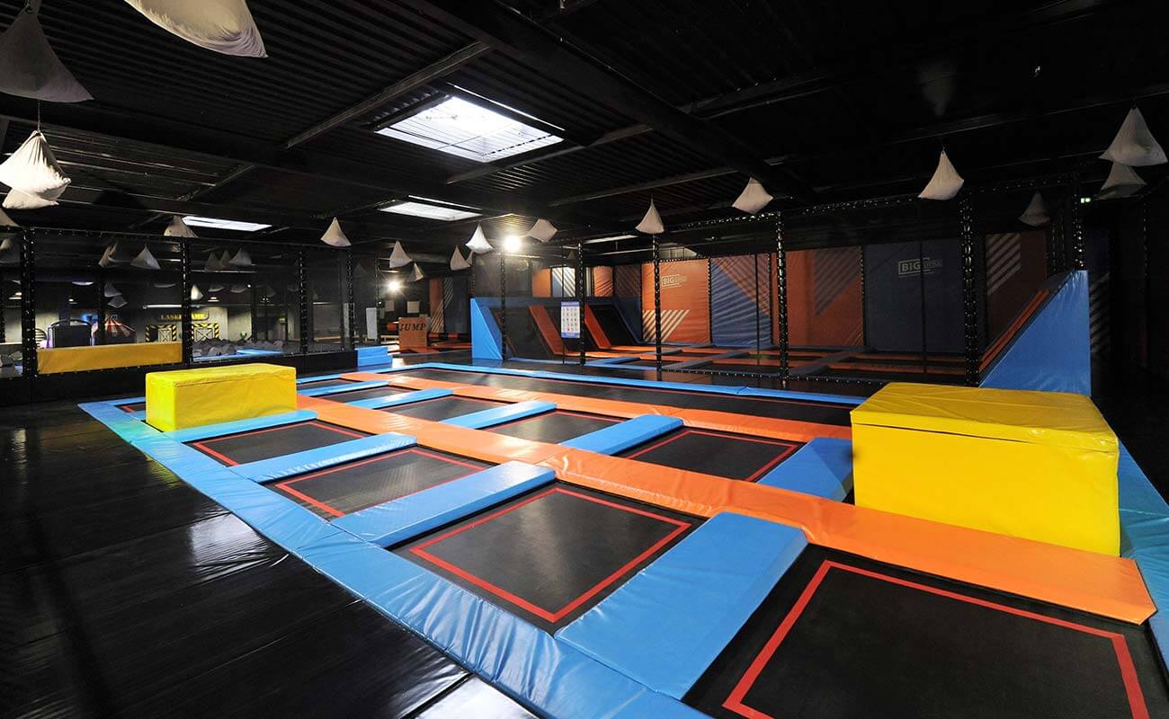 Zone de saut libre (Main Court) du Trampoline Park Big Little à Wittenheim, installée par Play In Business, avec toiles de saut, tapis de protection bleus et oranges, et blocs en mousse jaunes.