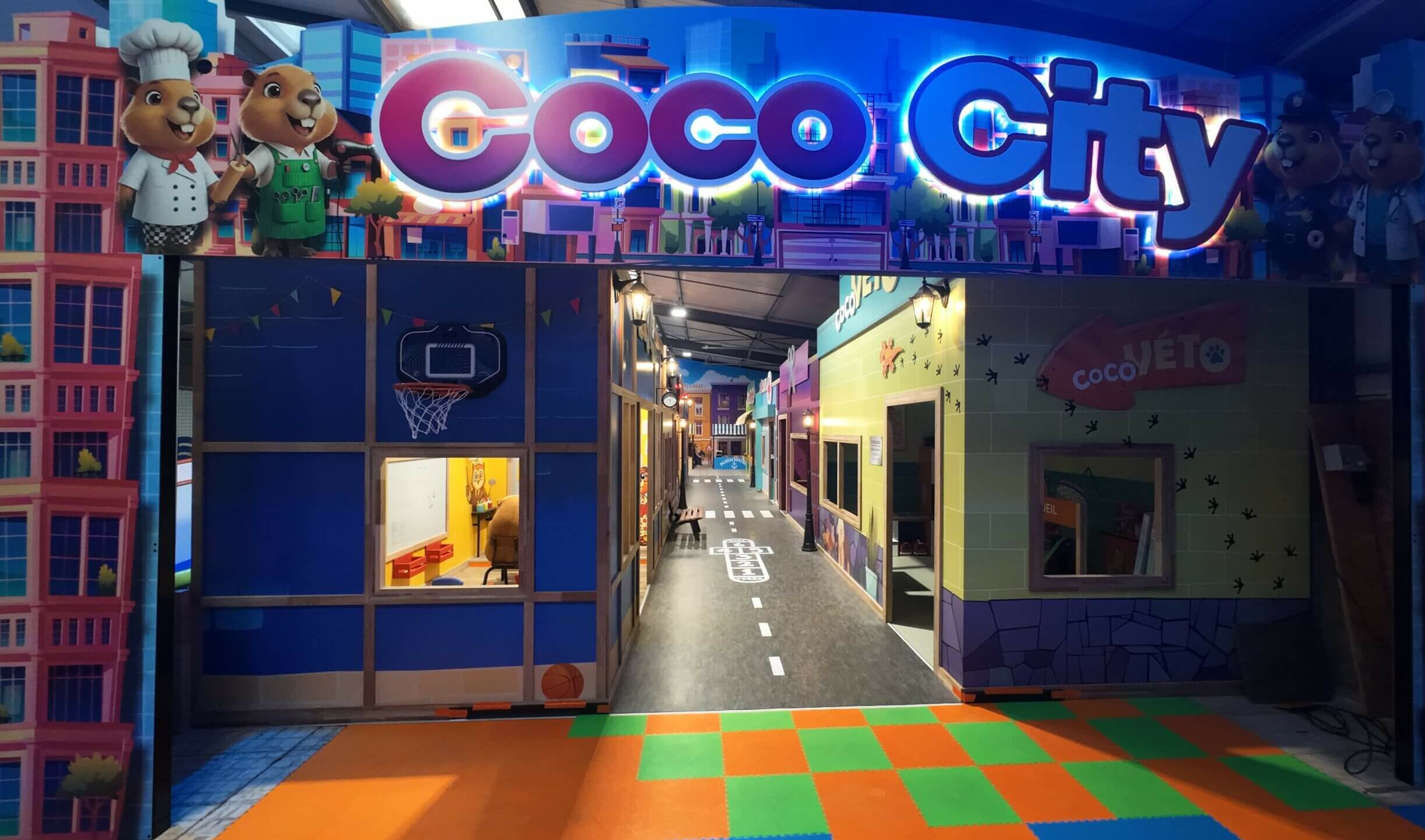 Entrée principale de la mini-ville immersive Coco City à Saint-Avold, un espace de jeux d'imitation sur mesure avec enseigne lumineuse conçu par Play In Business.