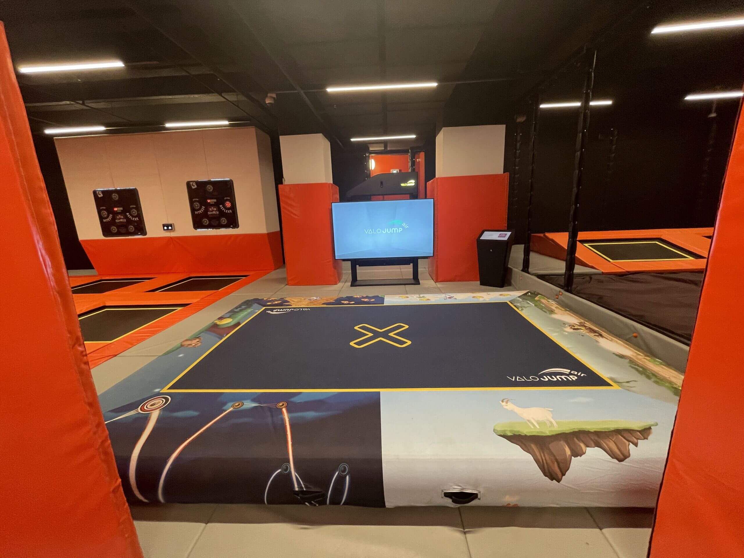 Installation de jeux interactifs dans un trampoline park : zone de saut connectée avec écran géant de réalité augmentée, aménagée par Play In Business pour les parcs de loisirs indoor.
