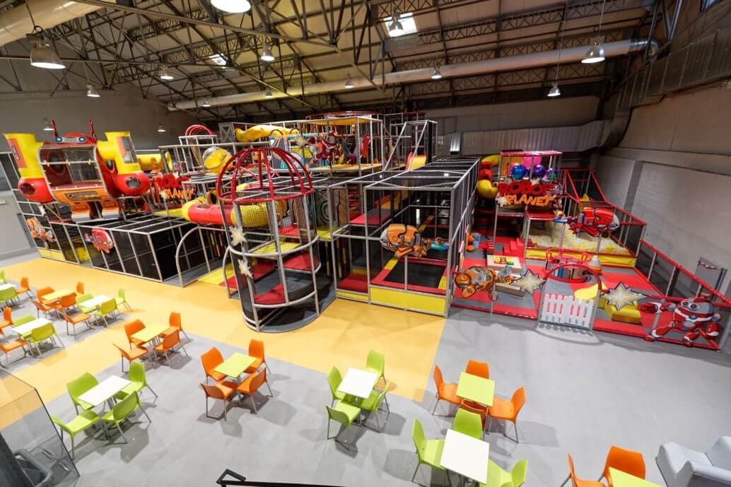 Plaine de jeux indoor géante et sur mesure sur le thème de l'espace et des robots, avec structures tubulaires et toboggans, aménagée par Play In Business pour le Cosmic Kids à Nancy.
