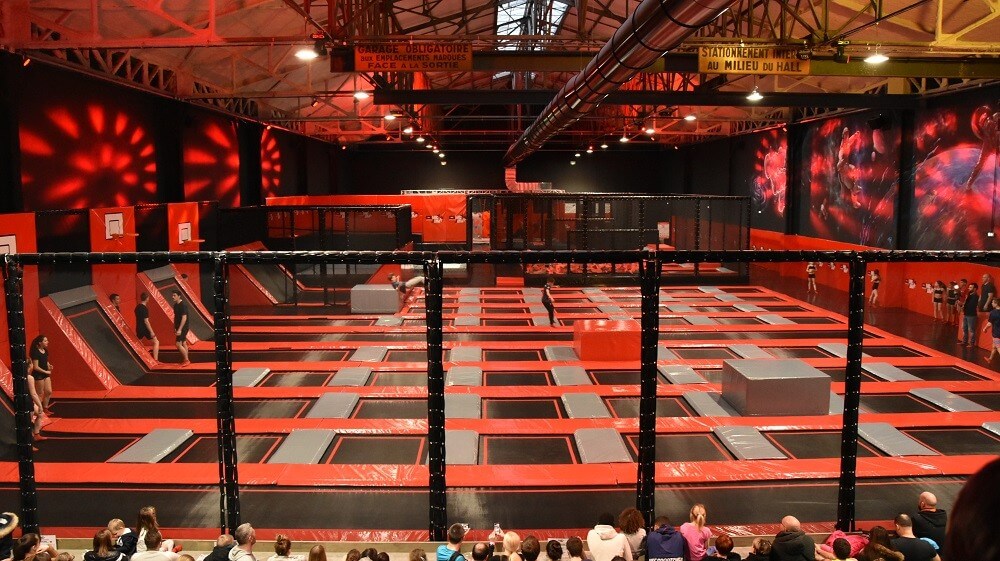 Immense Trampoline Park aux couleurs rouge et noir avec toiles de saut interconnectées et décoration galactique, conçu et installé par Play In Business pour le Cosmic Jump à Nancy.