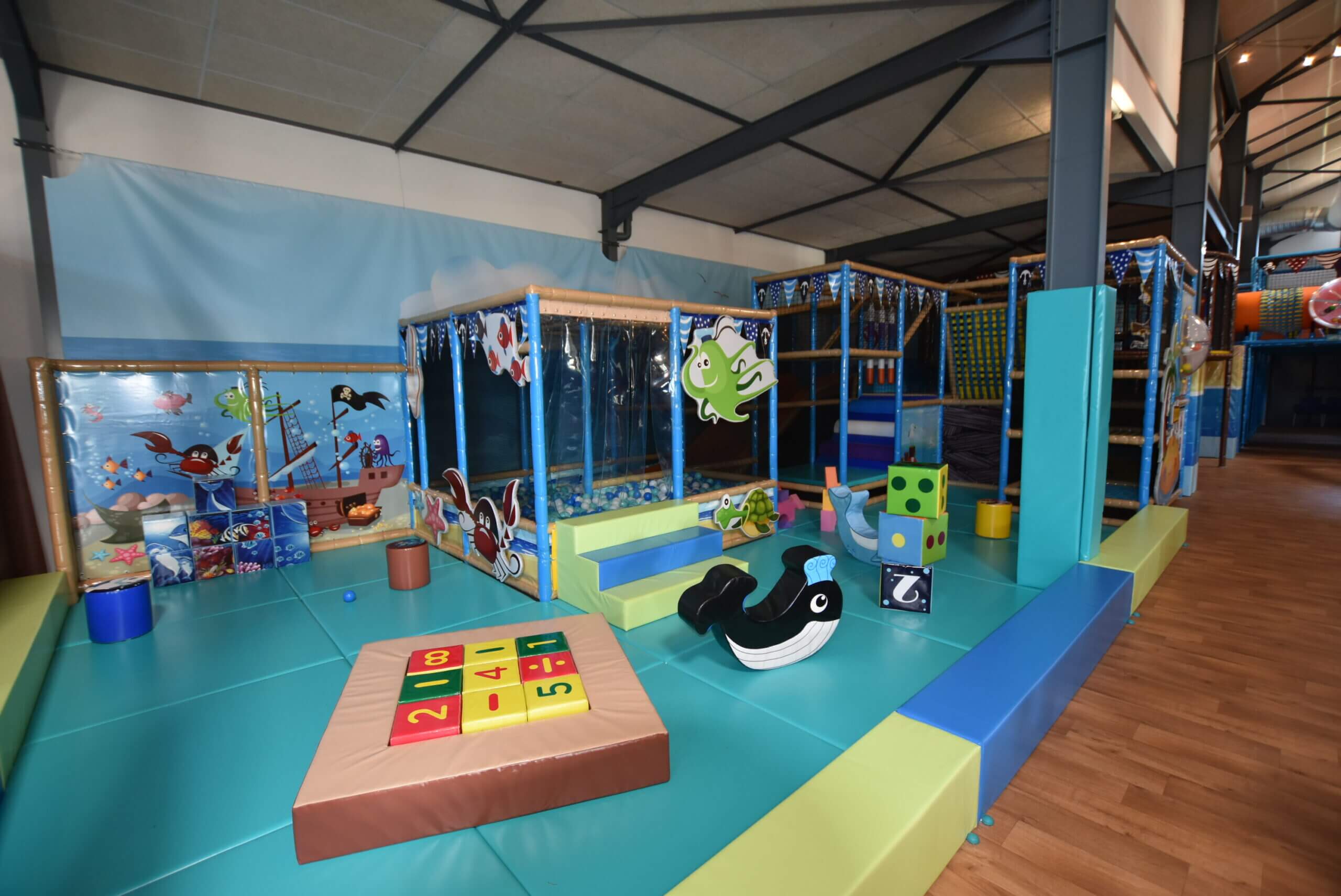 Espace de jeux sécurisé pour tout-petits (toddler zone) sur le thème marin, avec modules en mousse ludiques et piscine à balles, aménagé par Play In Business pour le parc Hissého à Saint-Mitre-les-Remparts.