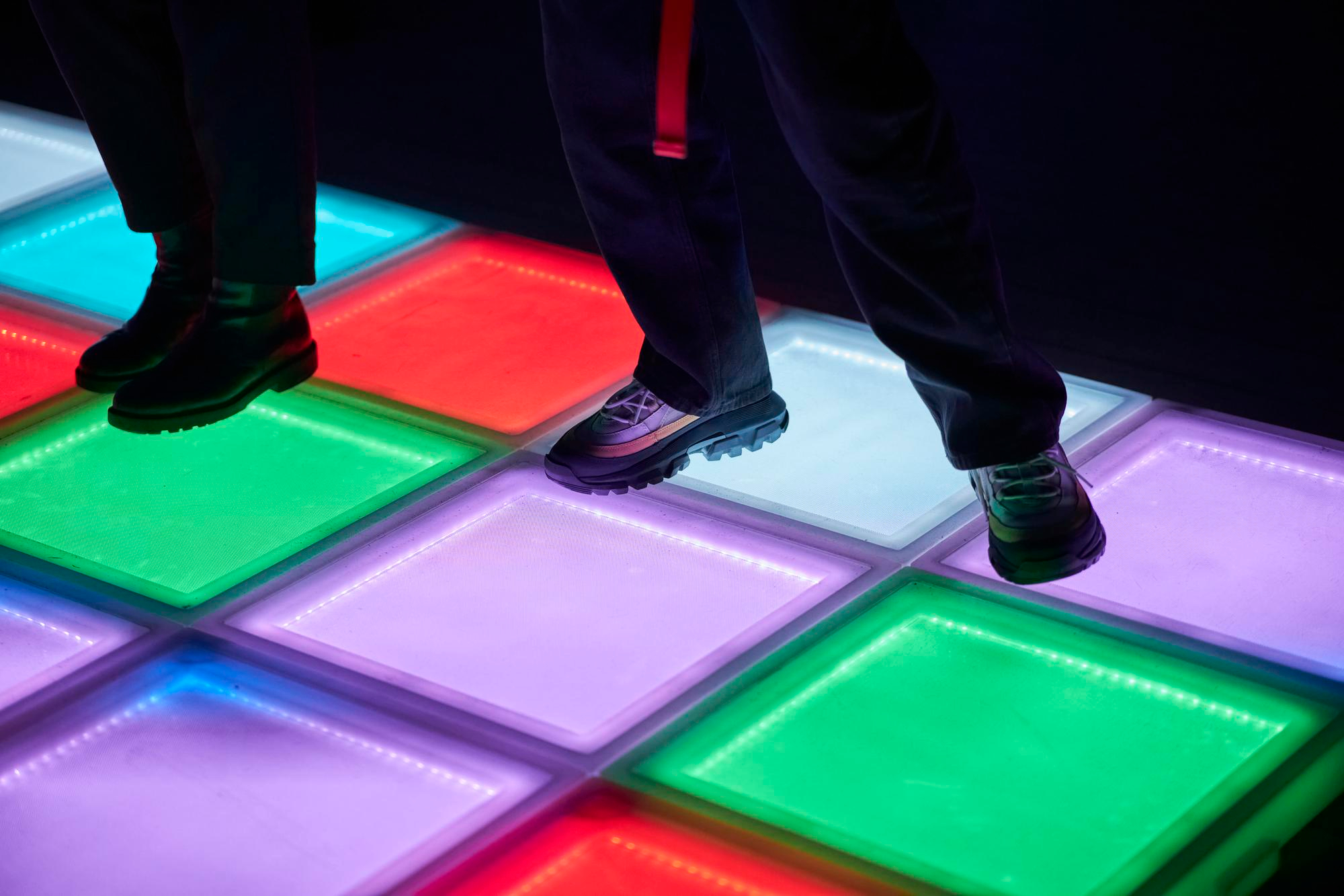 Joueurs s'amusant sur un sol lumineux avec dalles LED. Play In Business équipe votre parc indoor avec les dernières innovations en matière de jeux interactifs.