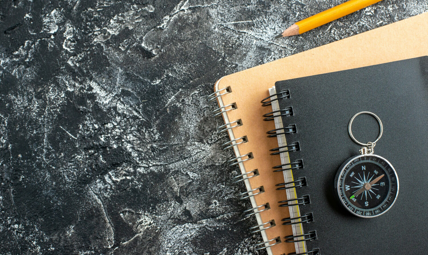 Carnets, crayon et boussole symbolisant l'histoire, la direction et l'expertise de Play In Business, fabricant de parcs de loisirs depuis 30 ans.