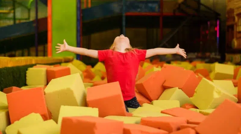 A happy child in a foam pit at an indoor play park built by Play In Business.
