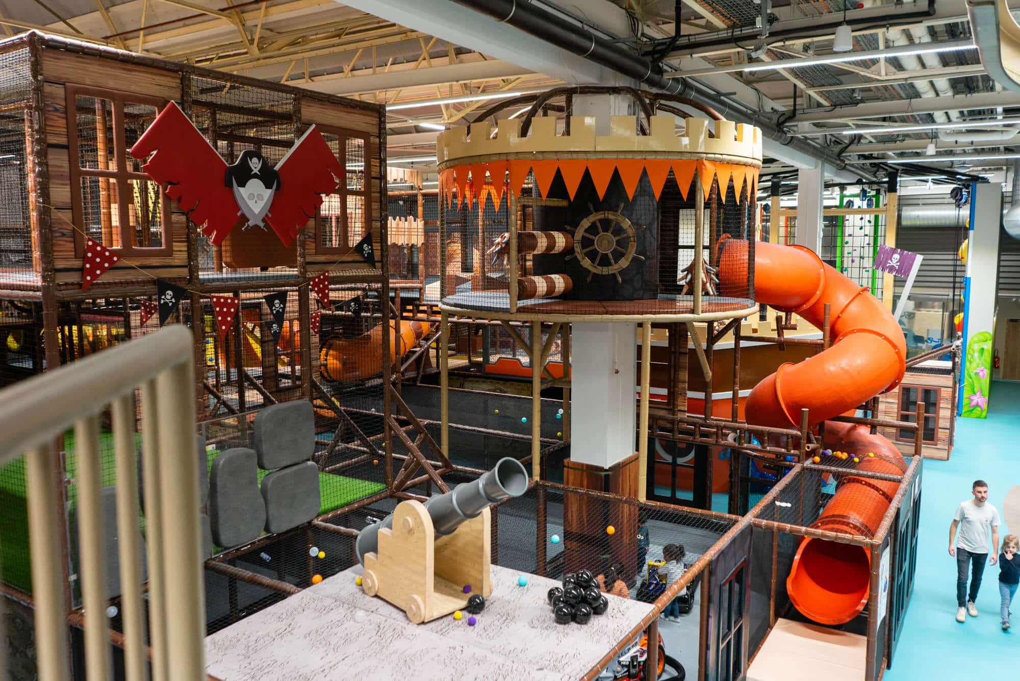 Détail de la plaine de jeux immersive L'Île de Tortuga à Lille aménagée par Play In Business, montrant des décors pirates sur-mesure incluant vigie, canons et pontons en bois.