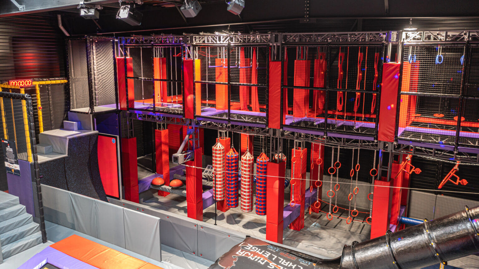 Parcours Ninja indoor rouge et noir avec obstacles suspendus et chronomètre, réalisé par Play In Business pour le parc de loisirs Wonderful-Land.