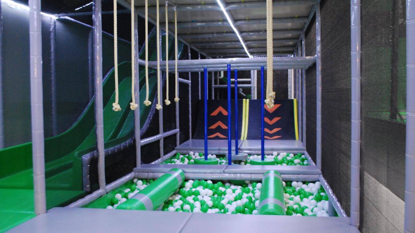 Parcours d'obstacles type Ninja avec cordes suspendues et piscine à balles verte et blanche, conçu et installé par Play In Business pour le complexe Jump Park 276.