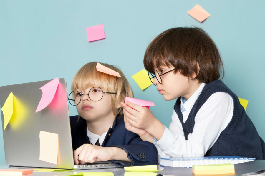 Deux enfants jouant aux entrepreneurs devant un ordinateur. Play In Business est votre partenaire stratégique pour l'ouverture et la rentabilité de votre parc de loisirs.