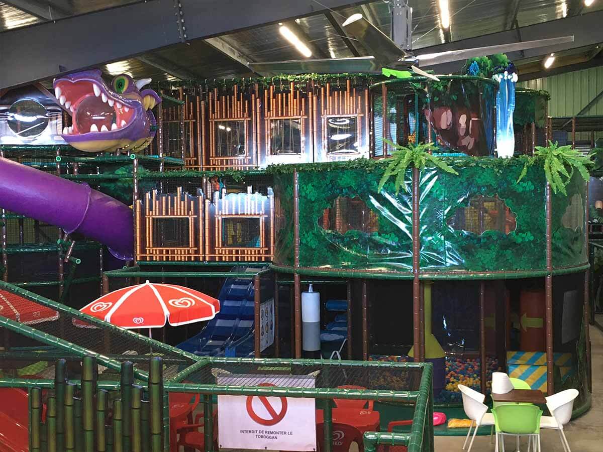 Grande structure de jeux indoor sur-mesure sur le thème de la jungle avec une tête de dinosaure géante, conçue et installée par Play In Business pour le parc Happy Kids à Saint-leu.