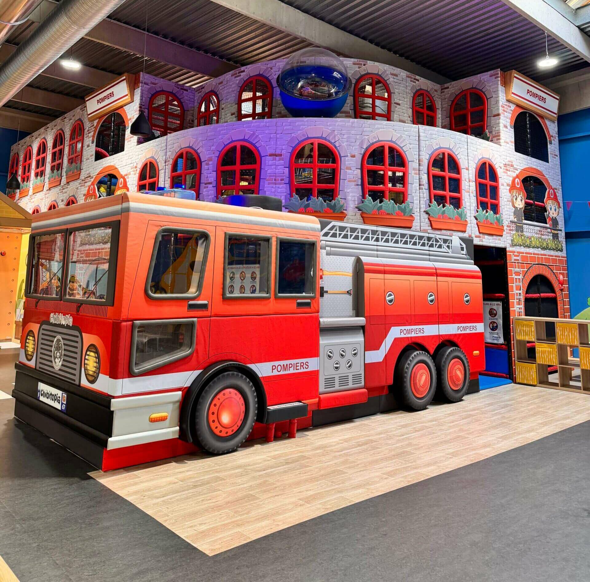 Structure de jeu indoor sur-mesure spectaculaire sur le thème des pompiers, illustrant la capacité de Play In Business à créer des décors immersifs complets.