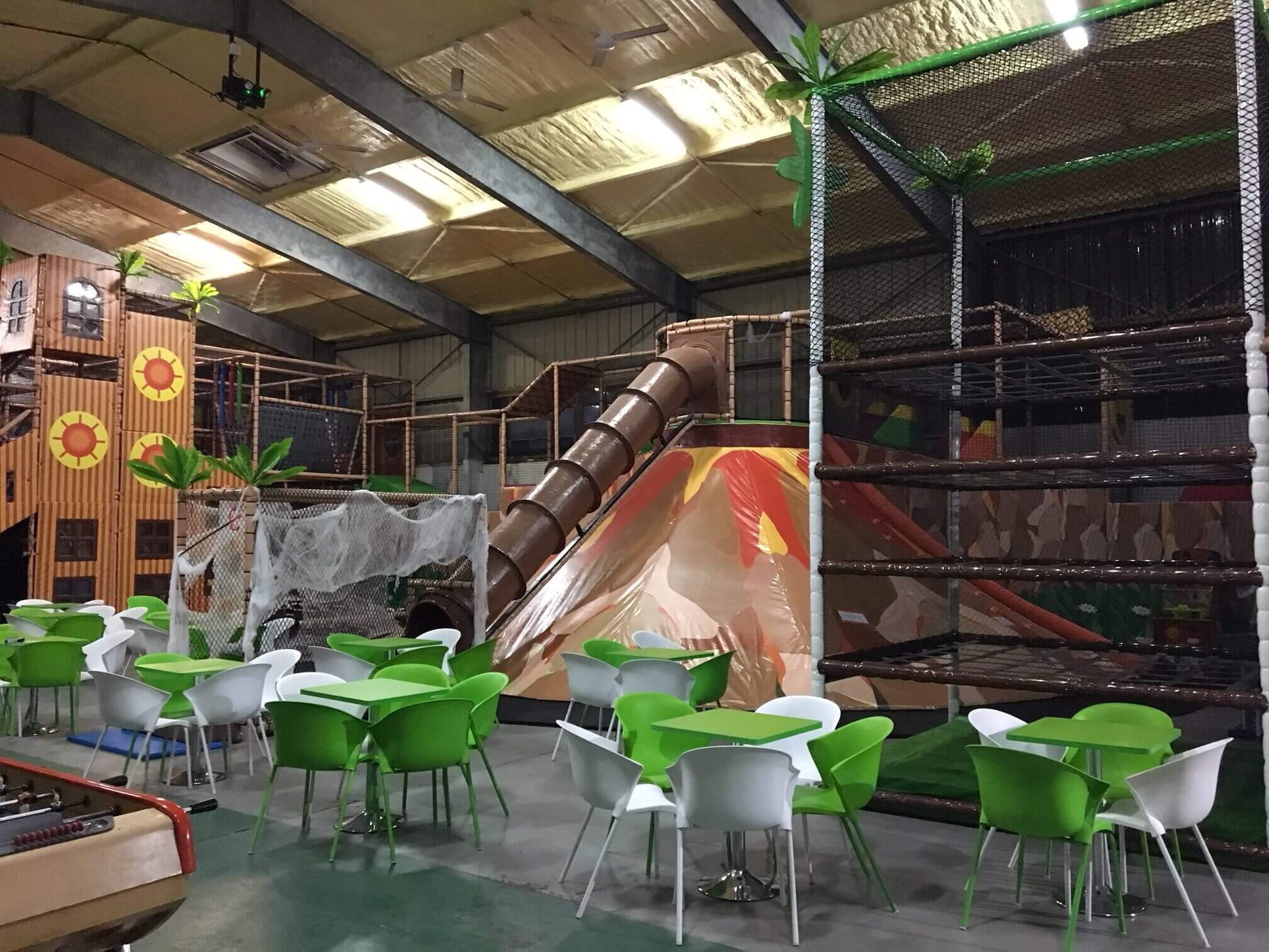 Détail de la structure de jeux indoor de Happy Kids à Saint-Pierre : toboggan tubulaire marron s'intégrant dans un décor de volcan immersif créé par Play In Business.
