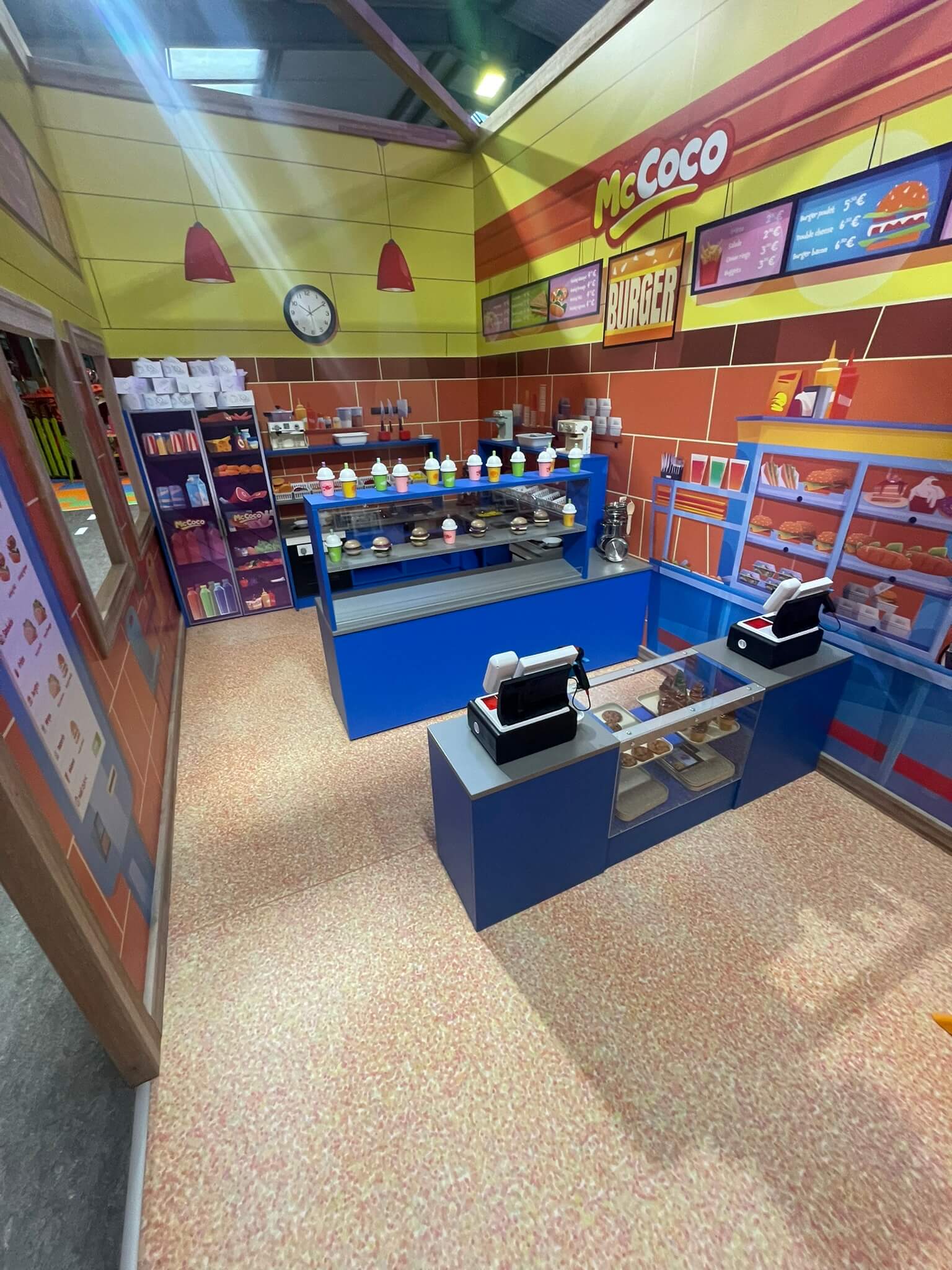 Jeu d'imitation fast-food avec comptoir, caisses et aliments factices pour parc de loisirs indoor.