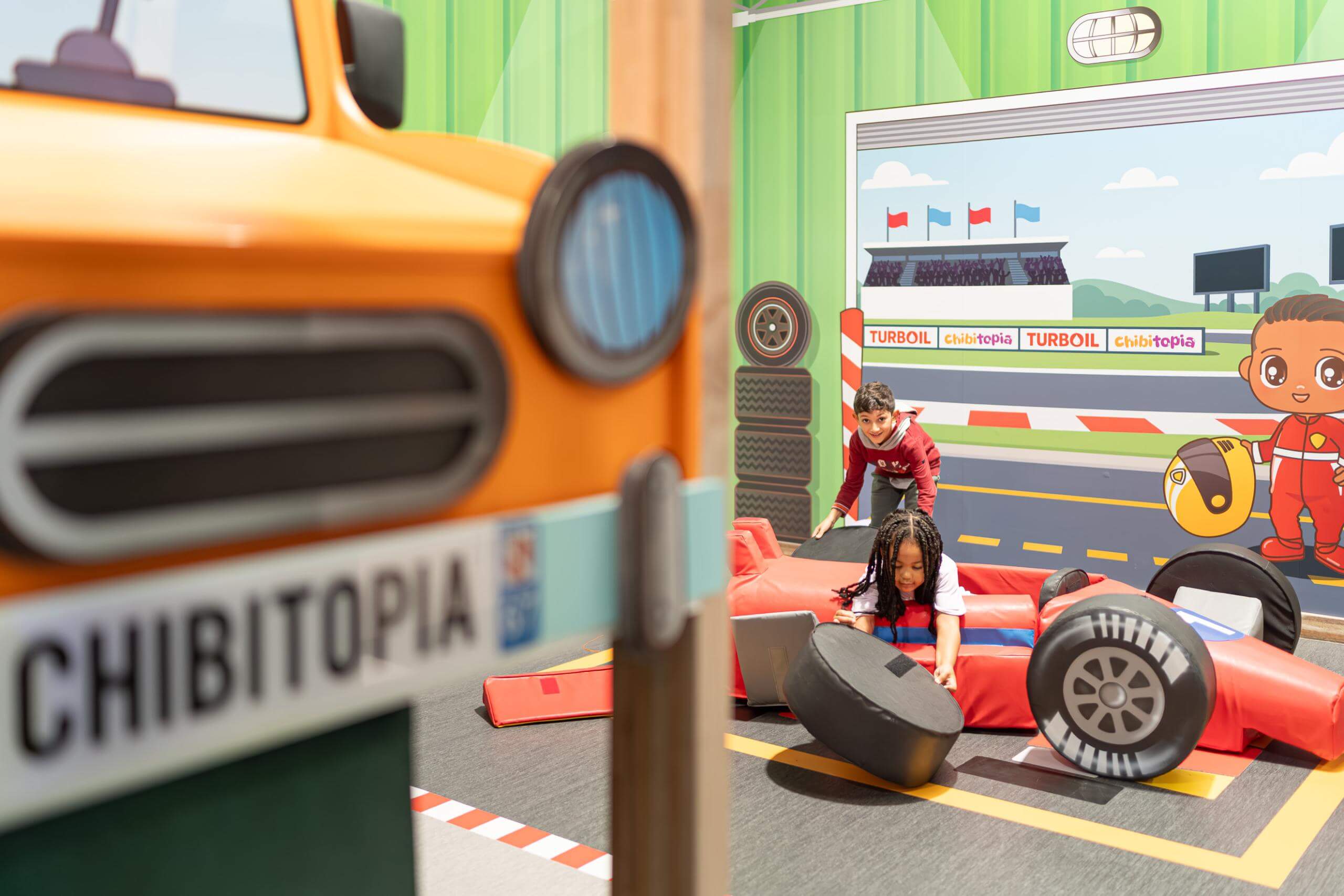 Façade du jeu d'imitation garage automobile avec enseigne et décors pour parc de loisirs indoor.