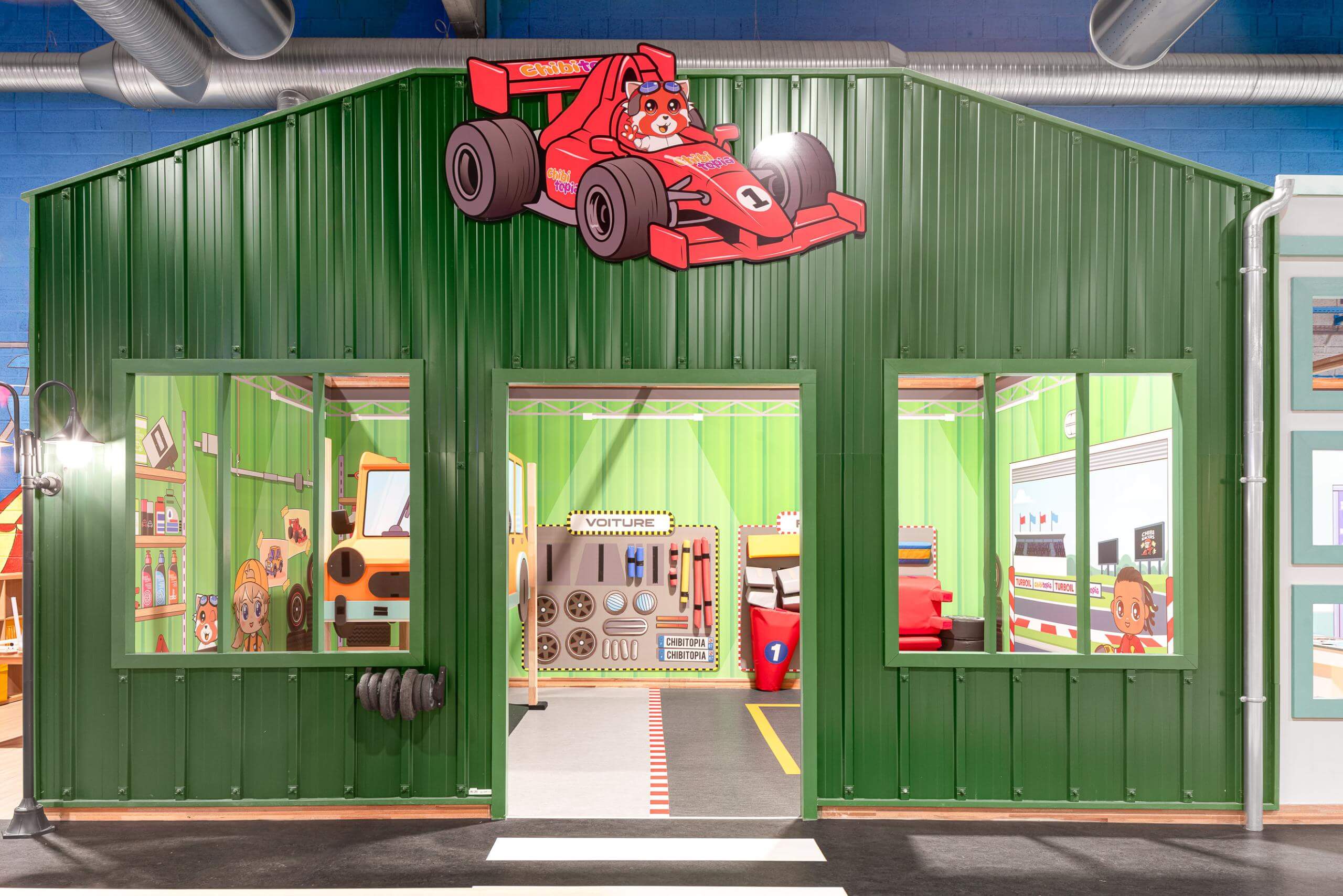 Enfant jouant avec une voiture de course en mousse démontable dans le jeu d'imitation garage mécanique.